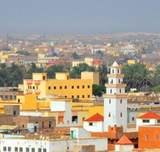 Nouakchott, Mauritania: skyline of the sprawling Mauritanian capital - colorful buildings, minaret, the palm trees of the 'Jardins de Nouakchott' and the coast-line